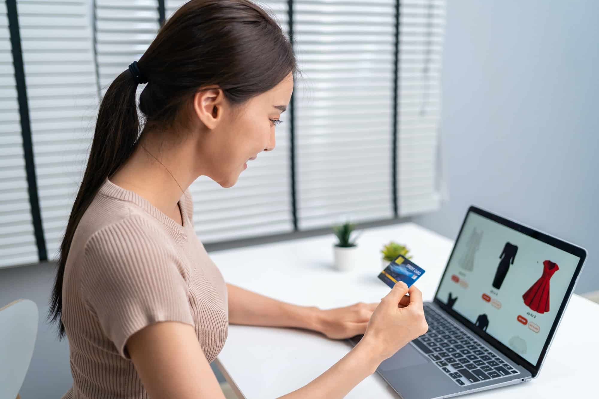 Une jeune femme asiatique utilise un ordinateur portable pour acheter des produits vendus en ligne.