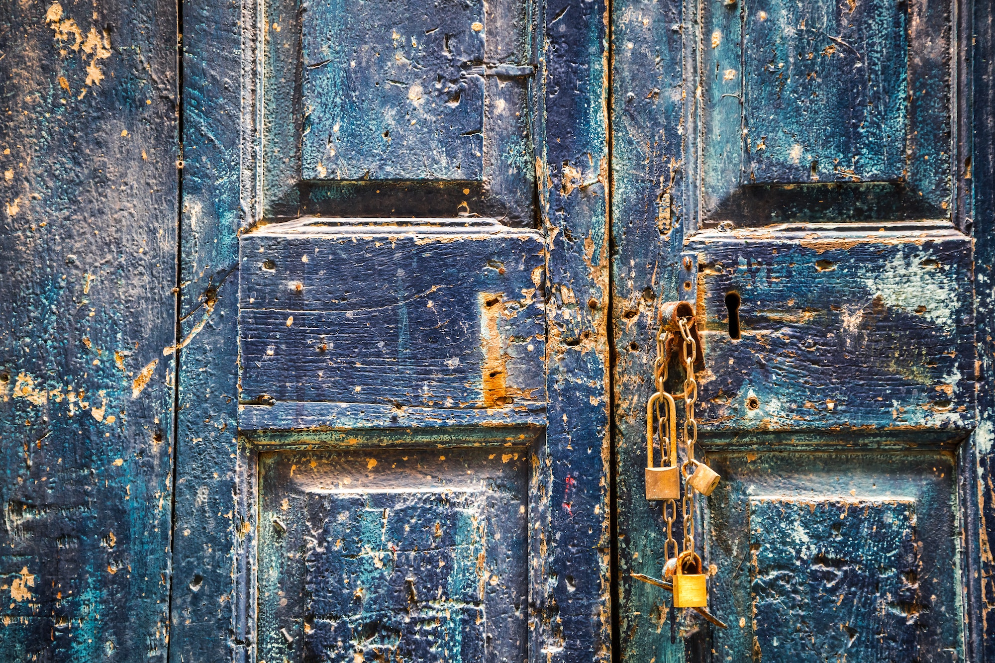 Antigua puerta azul de madera con candados