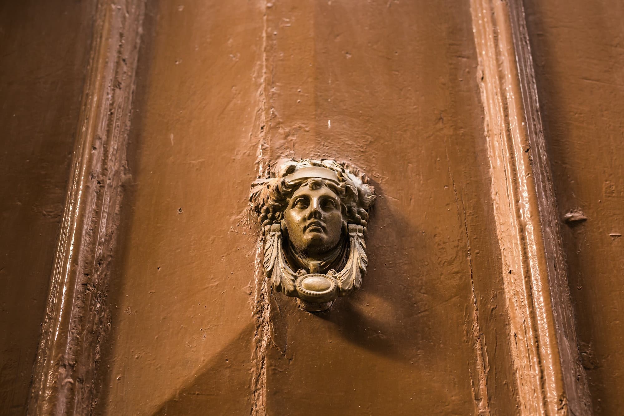 Empuñadura de puerta adornada tradicional o aldaba contra una puerta de madera