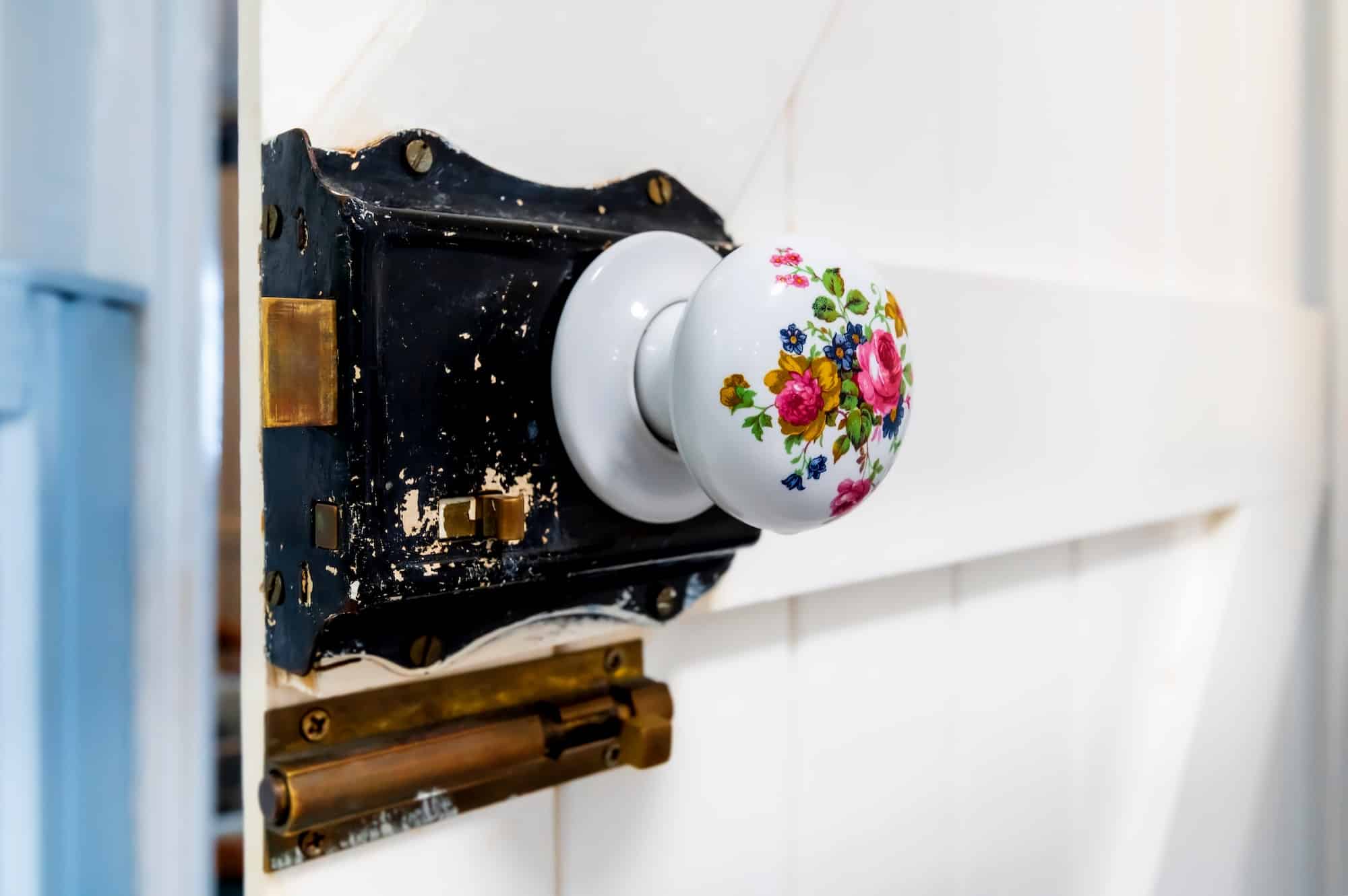 Close-up at Victorian style round porcelain floral decorated door knob on white wooden barn door