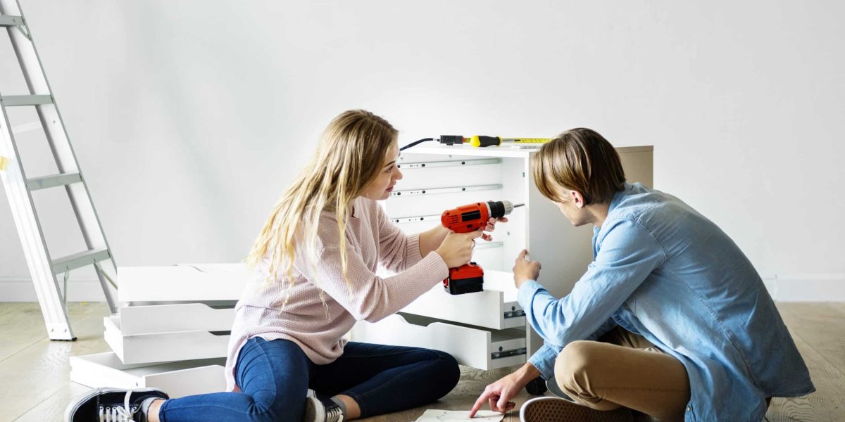 Woman using electronic drill install cabinet